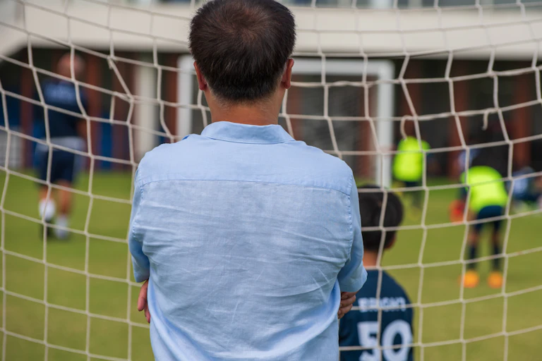 A man watches junior soccer