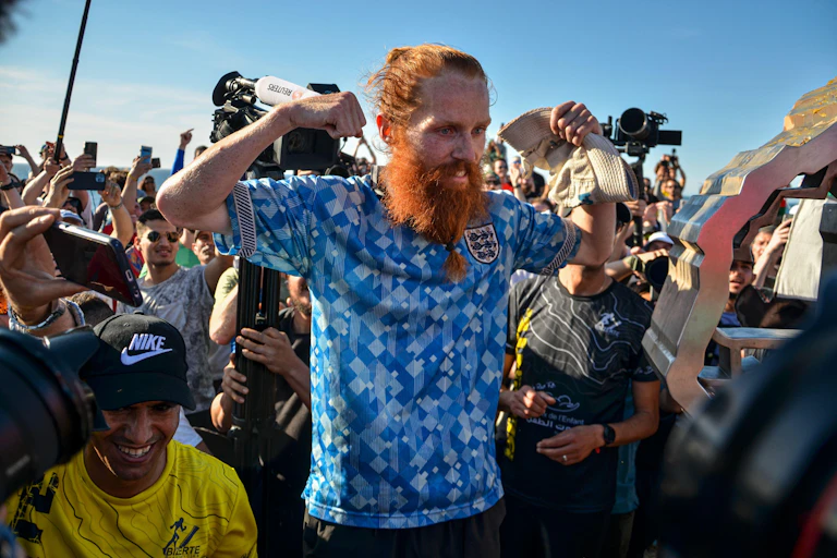 A photo of Russ Cook flexing his muscles for photographers.