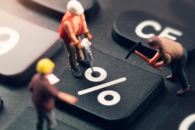 Three toy workmen working on a keyboard percent sign