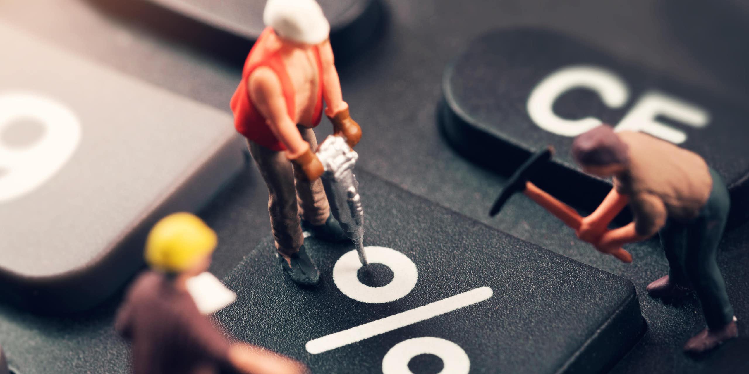 Three toy workmen working on a keyboard percent sign
