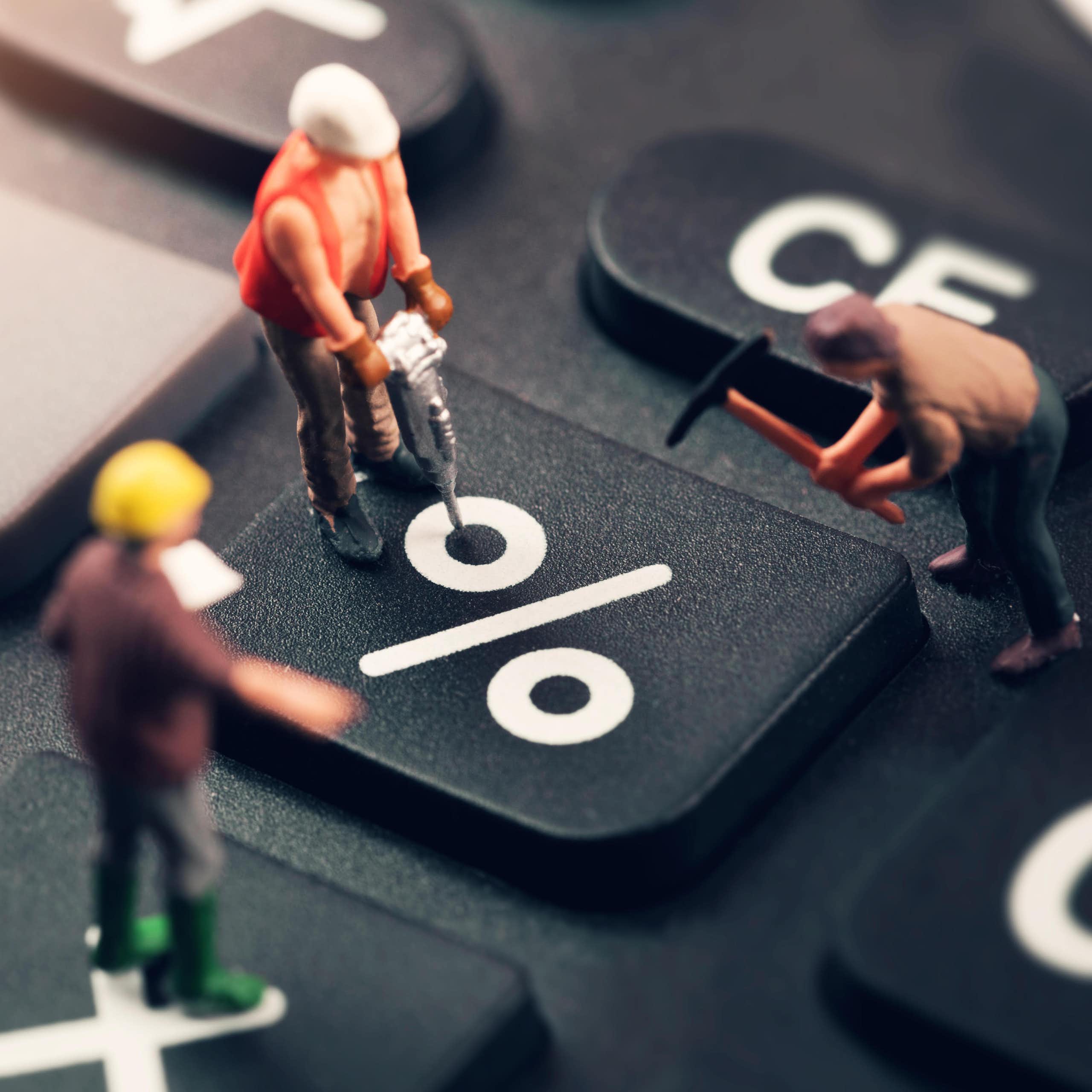 Three toy workmen working on a keyboard percent sign