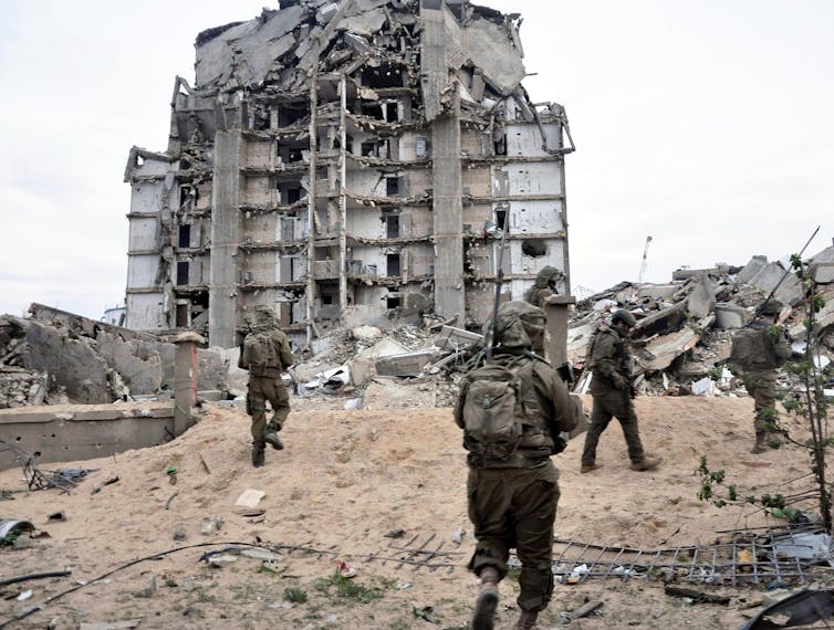 IDF troops patrol in Gaza amid rubble and damaged buildings.