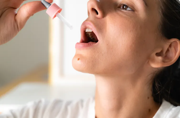 Person holding a dropper up to their mouth.