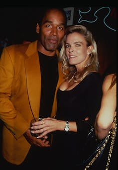 A Black man stands next to a white woman as they pose for a photograph.