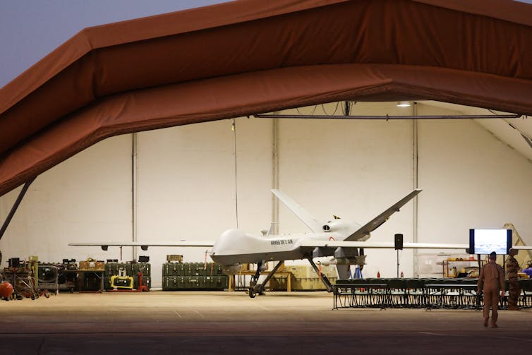 A white large drone in an airport hangar.