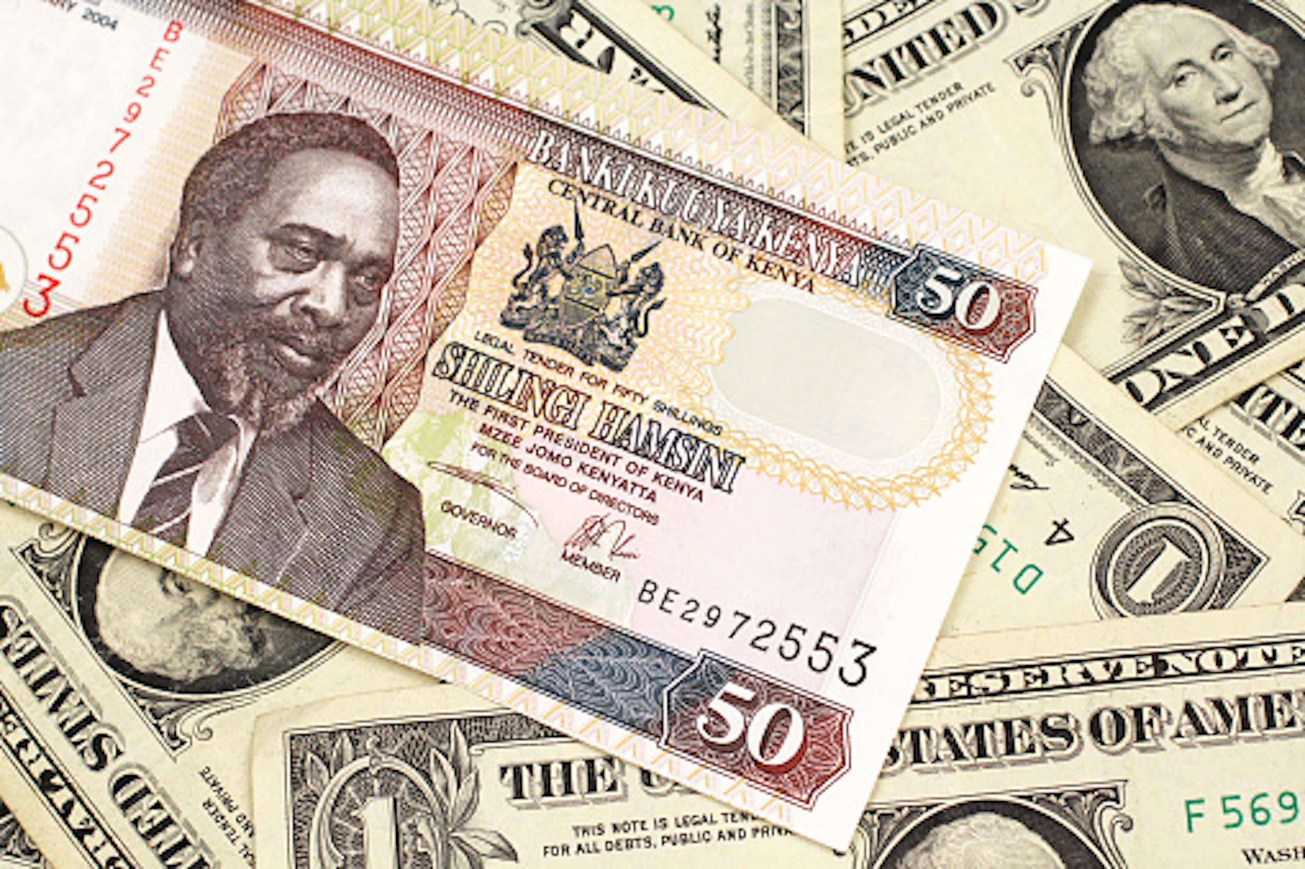 A close up image of a fifty Kenyan shilling bank note in macro with American one dollar bills