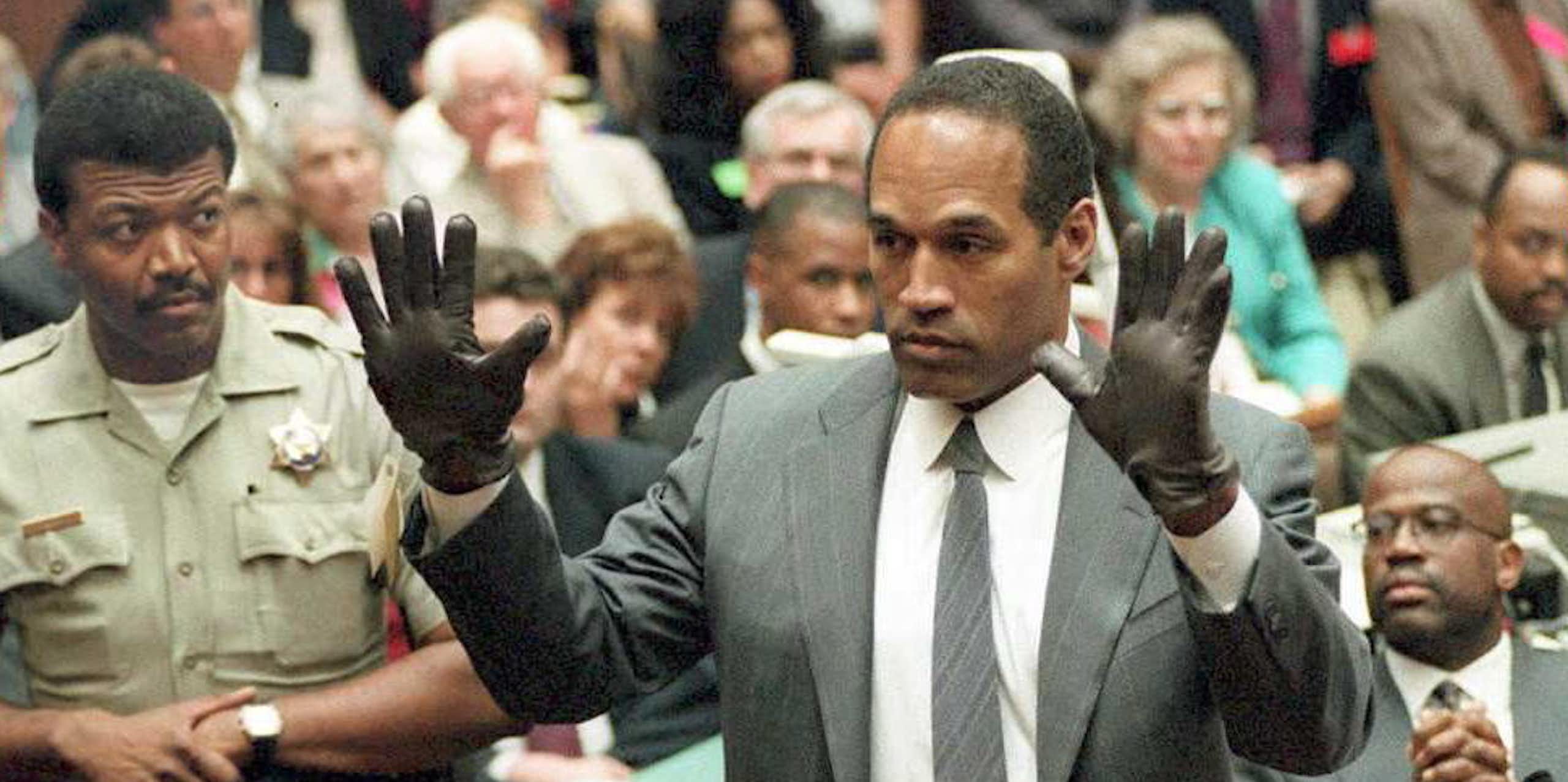 Black man holds up his hands as he wears black gloves.