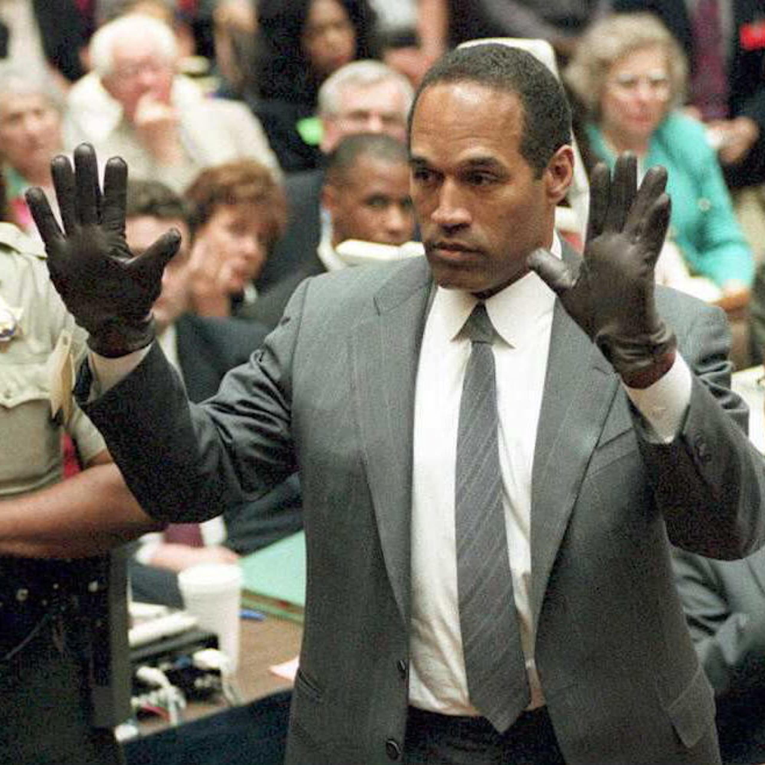 Black man holds up his hands as he wears black gloves.