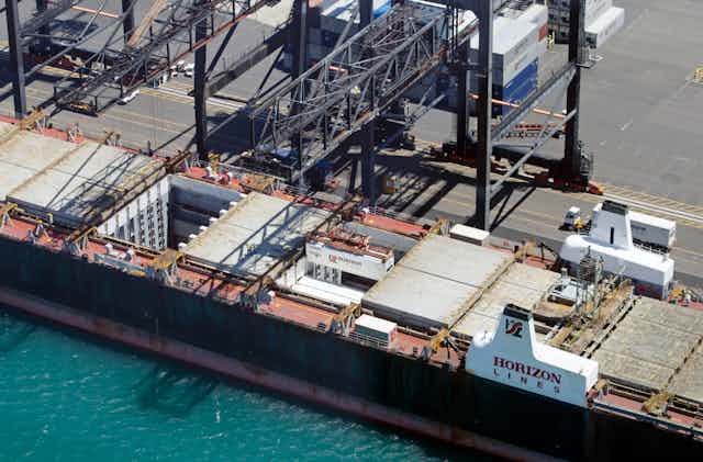 Gantry cranes are seen loading containers into the hold of a cargo ship in Honolulu, Hawaii.