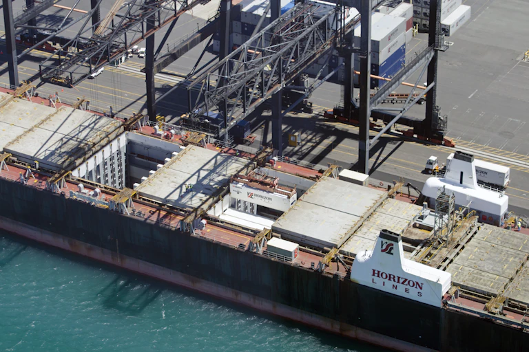 Gantry cranes are seen loading containers into the hold of a cargo ship in Honolulu, Hawaii.