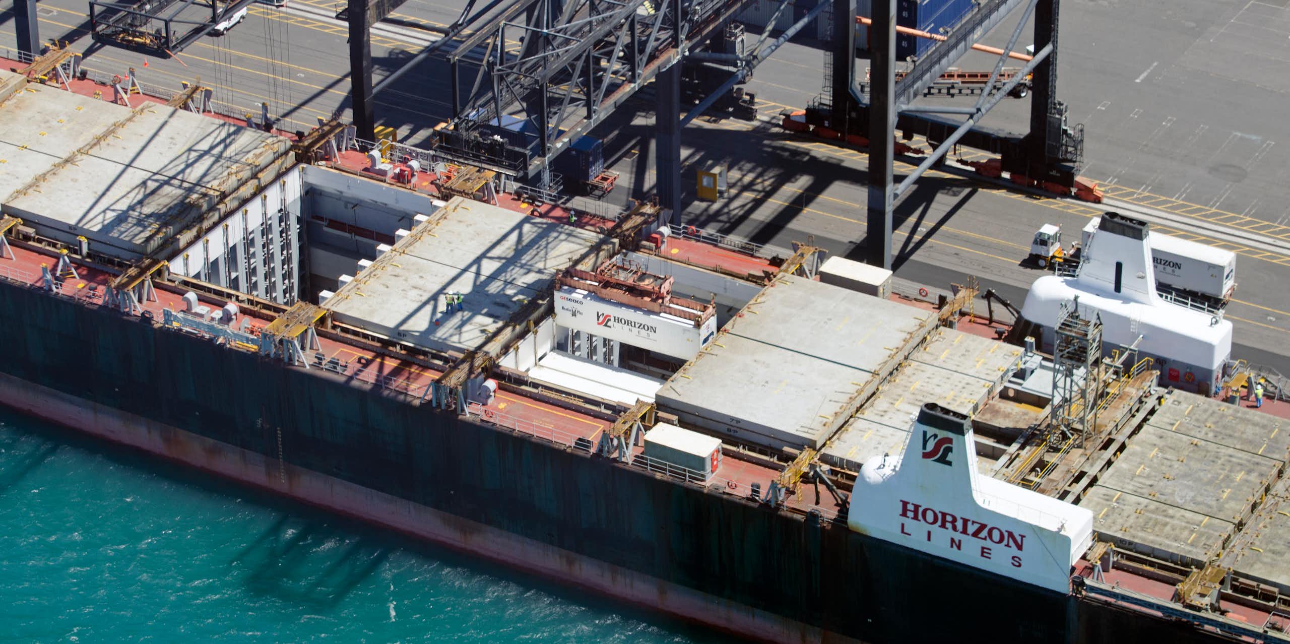 Gantry cranes are seen loading containers into the hold of a cargo ship in Honolulu, Hawaii.