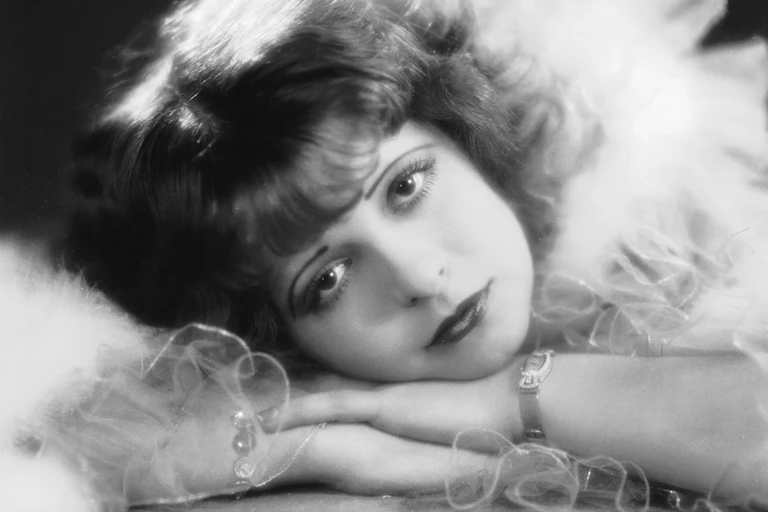 Black and white portrait of young woman bathed in light resting her head on her hands.