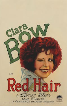 Movie poster that reads “Clara Bow in Red Hair.”  It shows a portrait of a red-haired young woman who is smiling and winking.