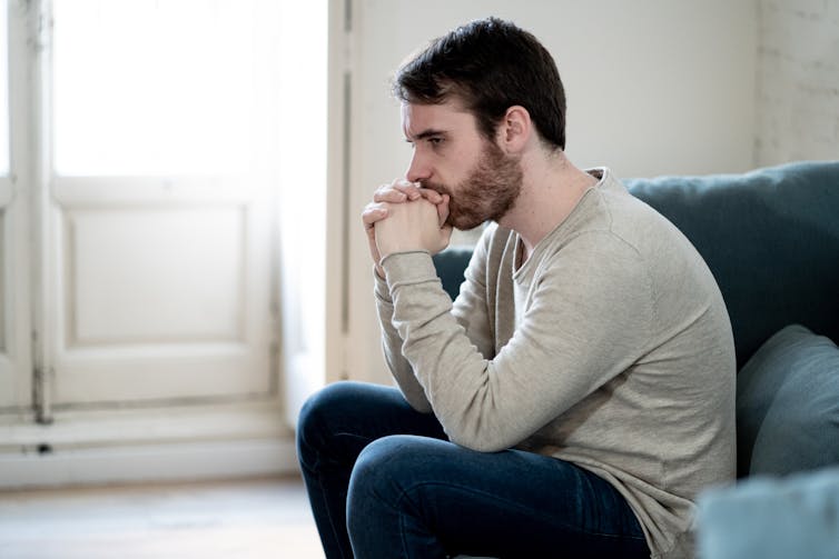 Man looks depressed, sitting in his living room