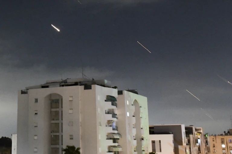 A white apartment building with streaks of light in the sky above it.