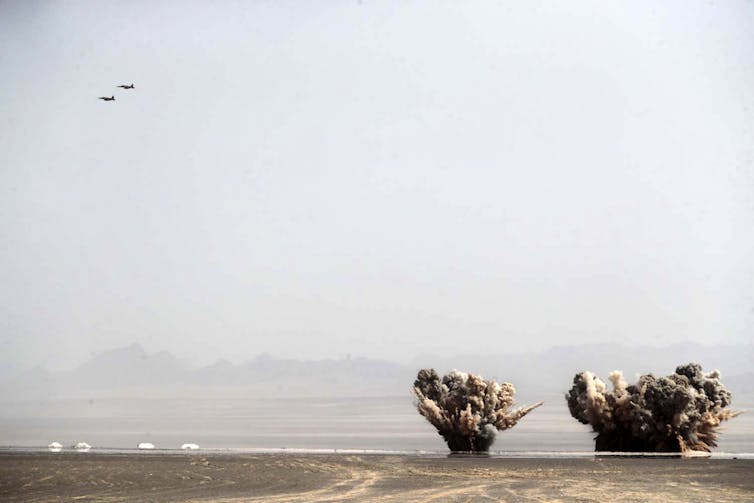 Planes fly above large explosions