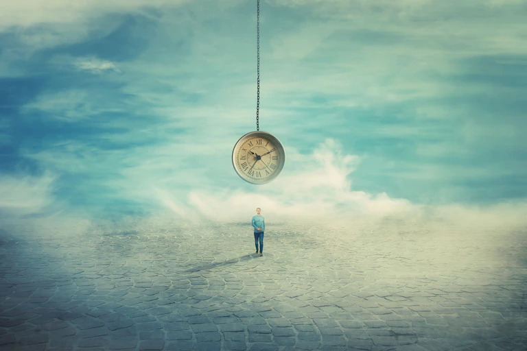 Surreal view as a man walking on a pavement road and a suspended clock on his back hanging from the sky.