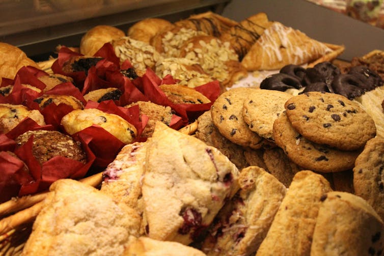 A display case with muffins, biscuits and pastries.
