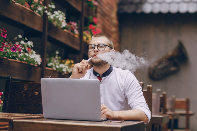 A man sitting in a cafe vaping.