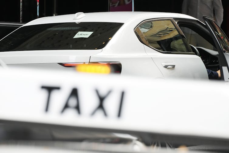Uber vehicle parked in front of a sign reading 'Taxi'