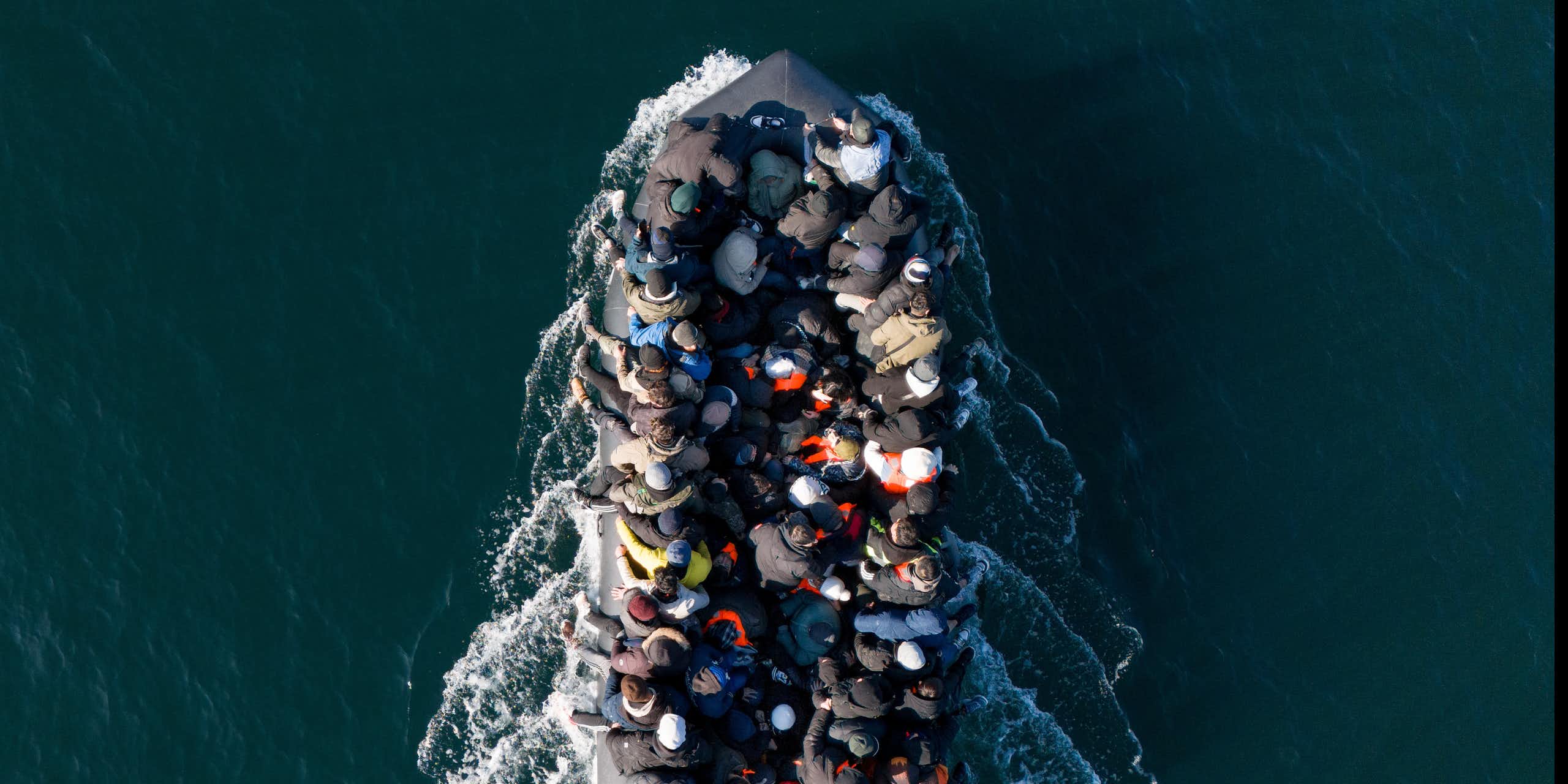 View from directly above of a small boat filled with people, surrounded by deep blue water