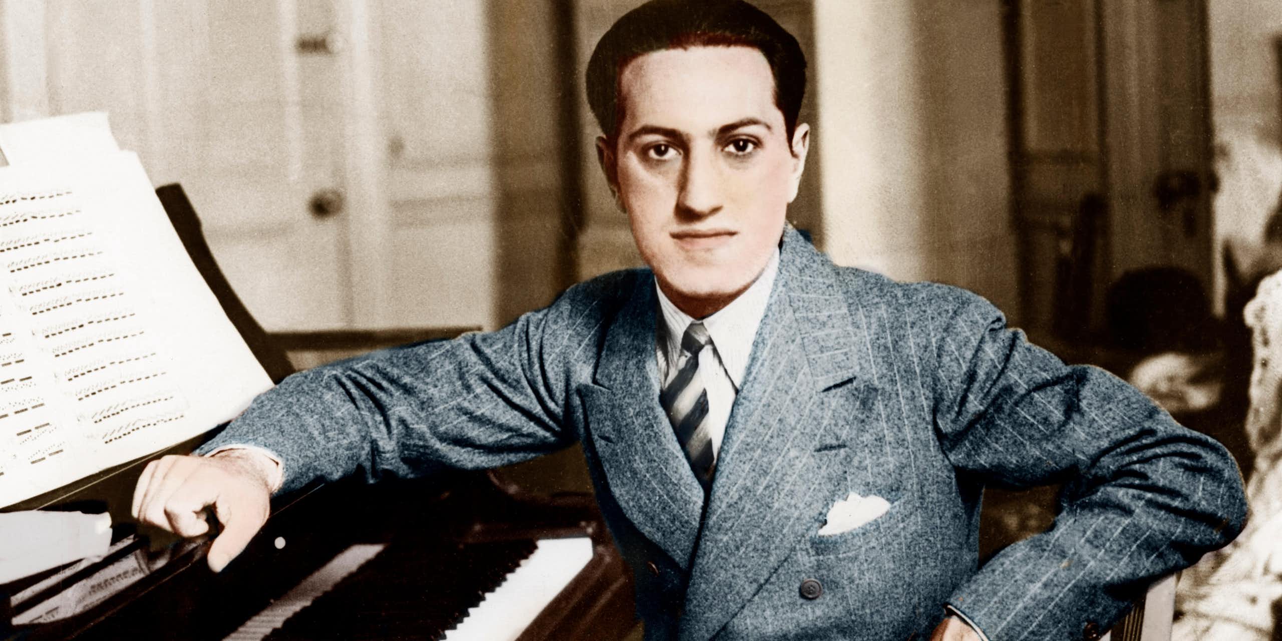 A young 1920s man (George Gershwin) sitting at a piano.