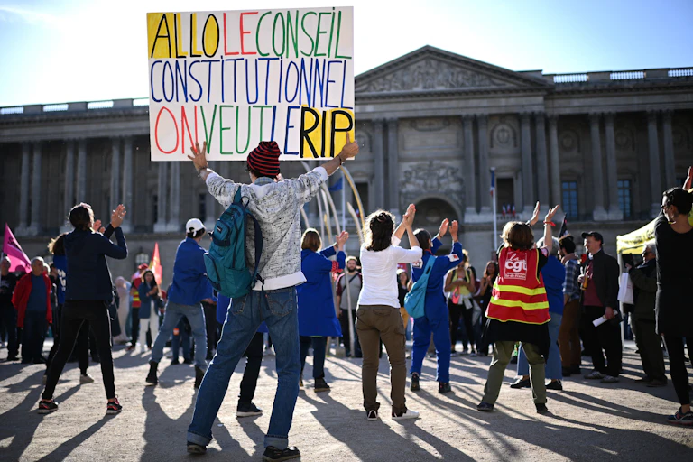 Un manifestant tient une pancarte sur laquelle on peut lire "Allo Conseil Constitutionnel, nous voulons le RIP (Référendum d'Initiative Partagé)" lors d'une manifestation à Paris suite à la décision du Conseil Constitutionnel de rejeter un second "Référendum d'Initiative Partagé", une initiative citoyenne visant à lancer un référendum sur la réforme des retraites du gouvernement (mai 2023).
