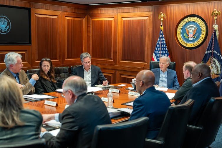 Joe Biden sat in a meeting room at a table full of smartly dressed people.