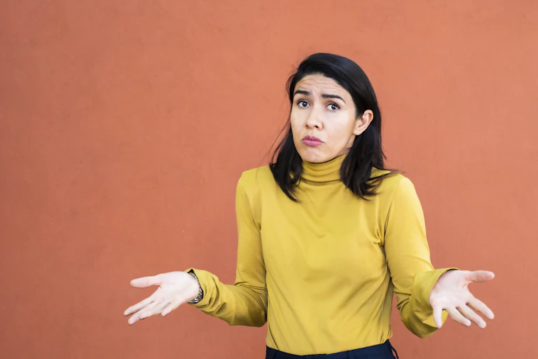 Woman shrugging with her hands pointing outward.