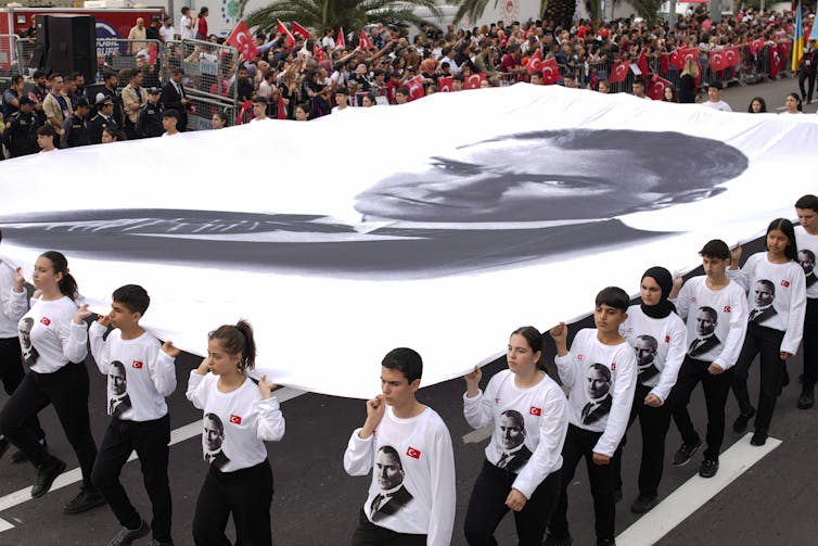 Young people carry a huge banner with a black and white photo of a man's face.