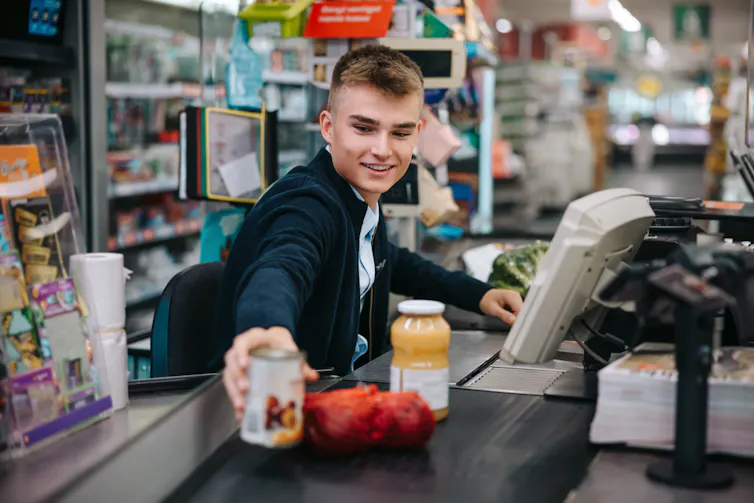 Jeune homme passant des articles à la caisse