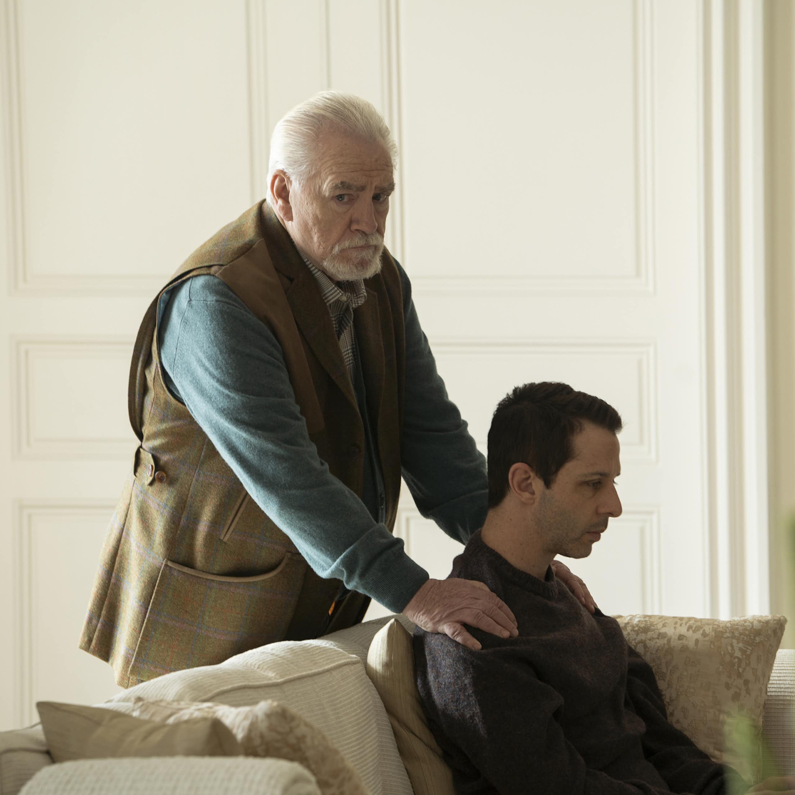 In a still from the HBO Series "Succession," patriarch Logan Roy, played by Brian Cox, is seen rubbing the shoulders of his son and heir apparent. Despite the seemingly affectionate gesture, the elder Roy looks off into the distance with a look of concern.
