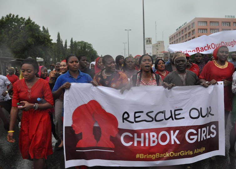 women marching while carrying a sign reading 'rescue our chibok girls'