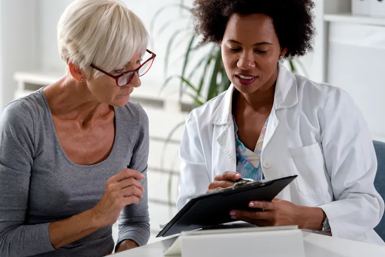 Une femme aux cheveux grisonnants consulte un médecin