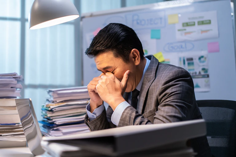 A tired office worker rubs his eyes