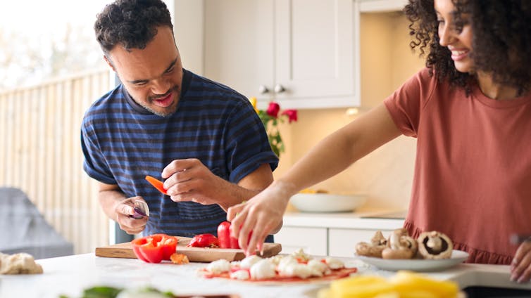 two people prepare food in kitchen. One appeared to have disability