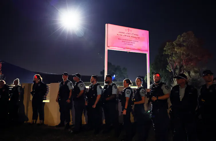 Police stand outside a church fence.