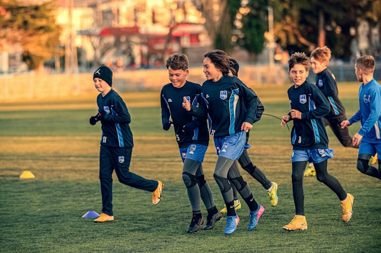 Boys in soccer uniforms jog on a field.