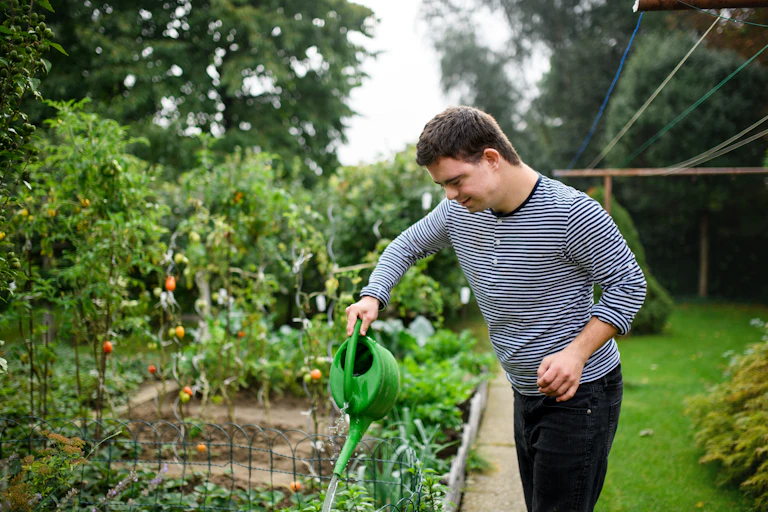 man with disability waters plants in garden