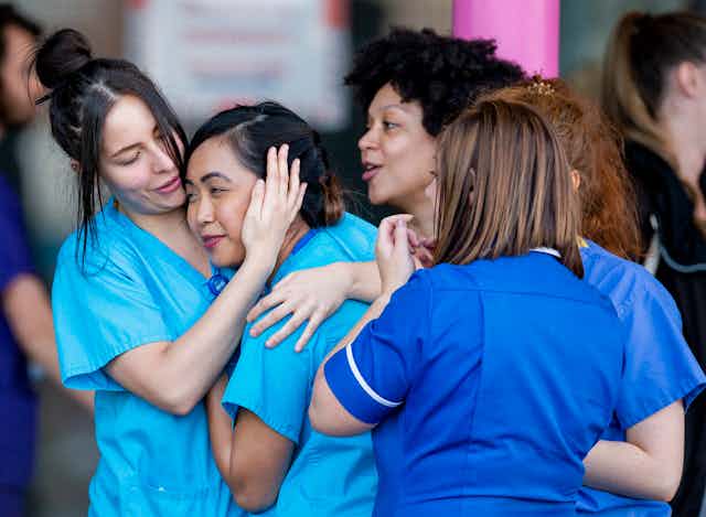 A group of NHS workers hugging each other.