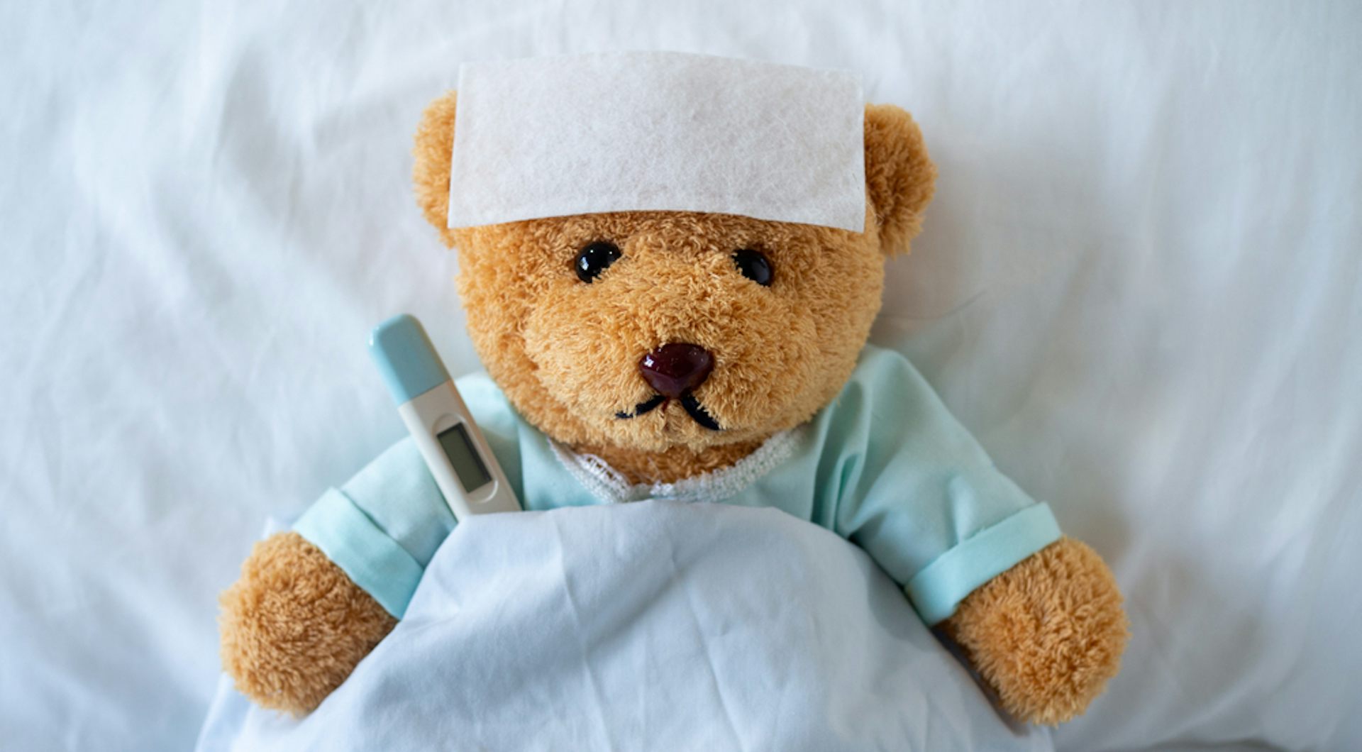 Un ours en peluche malade, allongé sur un lit avec une forte fièvre