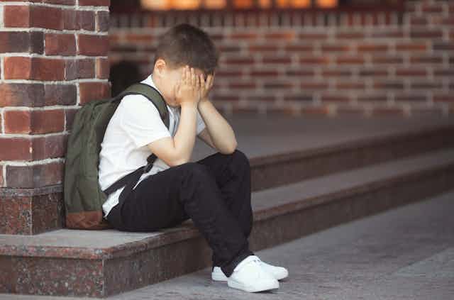 Sad boy on school steps