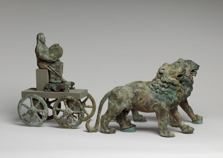 A bronze statuette of a woman riding a cart pulled by two lions.