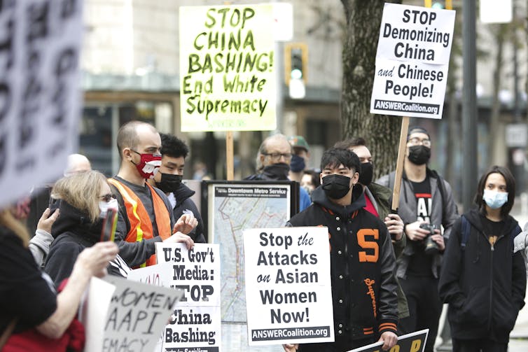 A group of demonstrators hold posters that oppose violence against Asian-Americans.