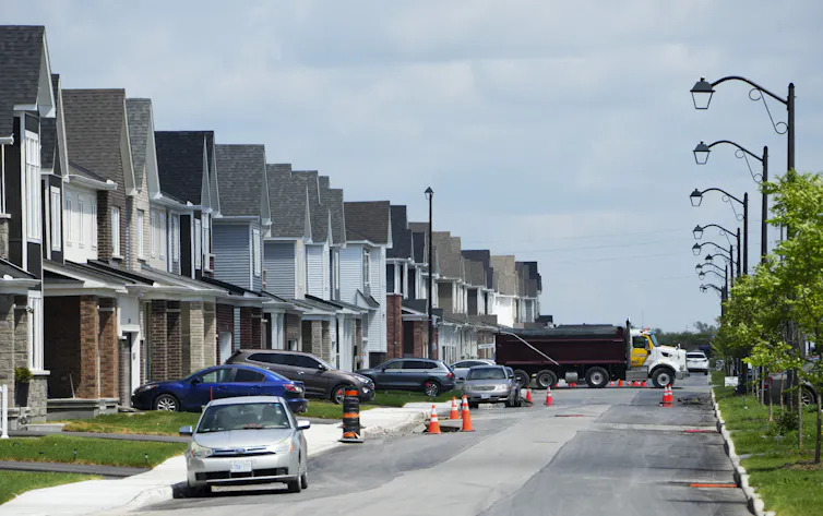 Une rangée de maisons neuves avec des voitures garées devant elles
