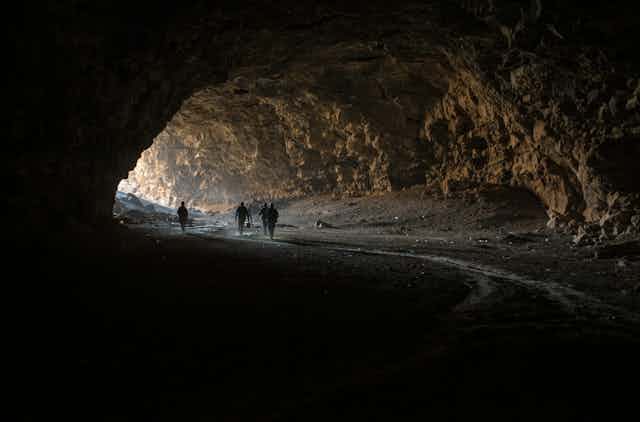 Photo of people walking into a large cave.