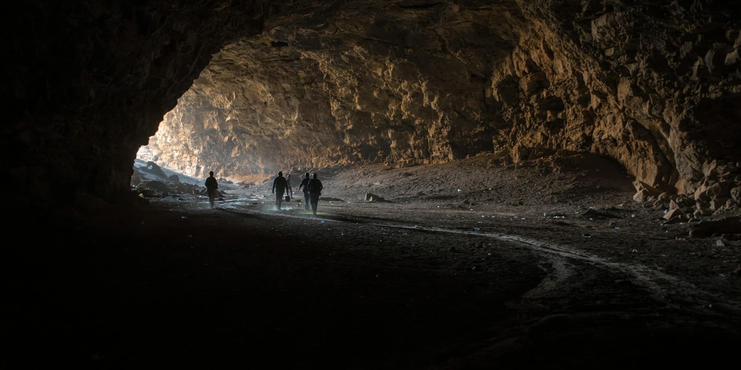 Photo of people walking into a large cave.
