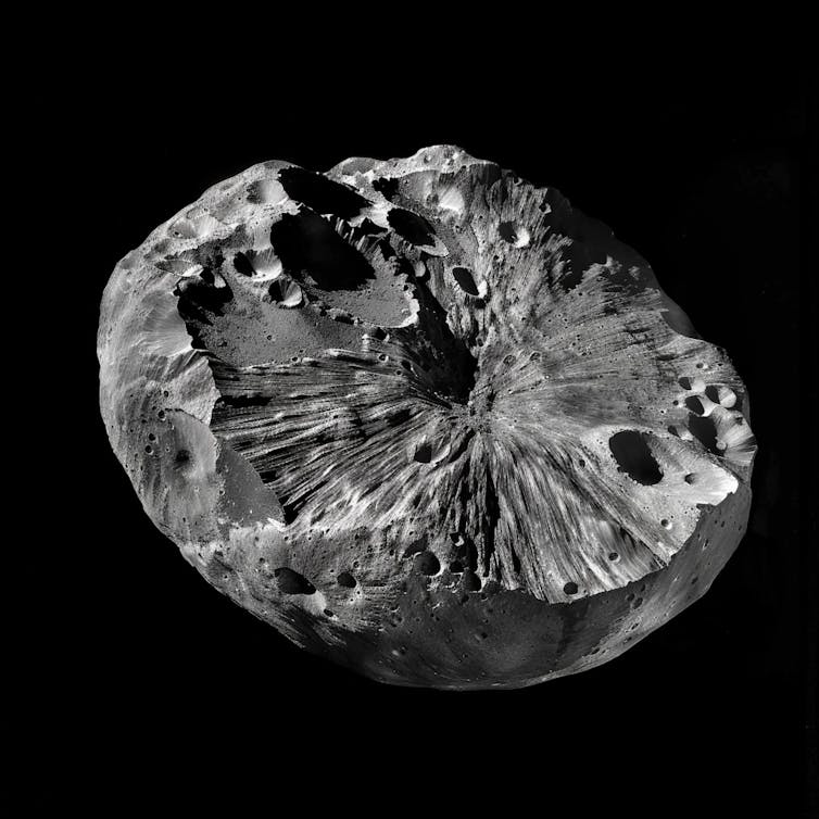 A half-globe shaped piece of grey cratered rock on a black background