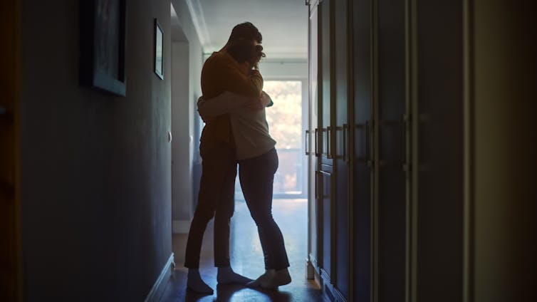 two people embrace in a hallway in supportive gesture