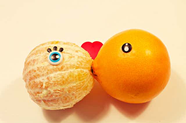 A peeled and an unpeeled orange kiss.